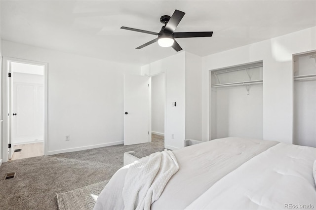 bedroom featuring multiple closets, carpet, ensuite bath, baseboards, and a ceiling fan