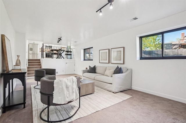 living room featuring carpet flooring, baseboards, and stairway