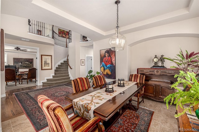 dining area with stairs, a tray ceiling, ceiling fan, and tile patterned floors