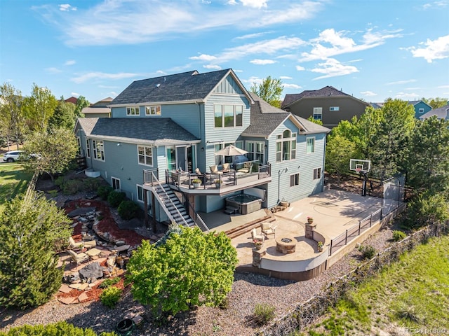 back of property with a wooden deck, a patio area, stairway, a shingled roof, and a fire pit