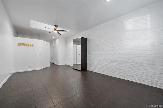 empty room featuring ceiling fan and brick wall