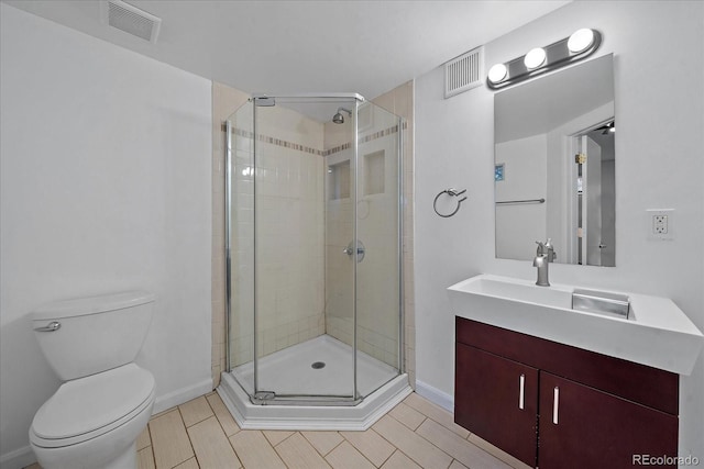 bathroom featuring tile patterned flooring, vanity, toilet, and a shower with door