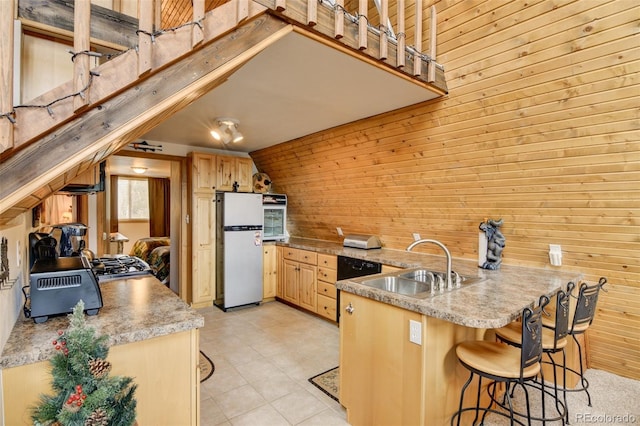 244 Lariat Loop, Hartsel, CO 80449 - kitchen with freestanding refrigerator, wooden walls, a peninsula, light brown cabinets, and a kitchen bar