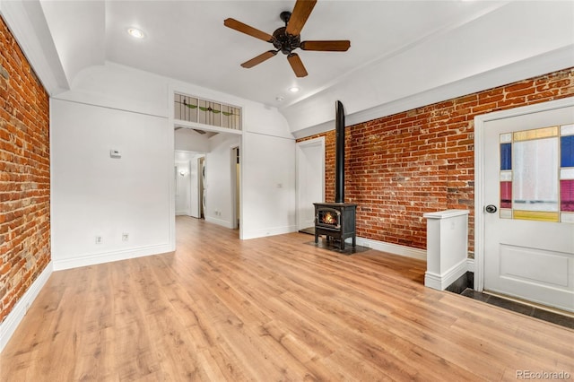 1748 S Logan St, Denver, CO 80210 - unfurnished living room with brick wall, vaulted ceiling, a ceiling fan, a wood stove, and light wood-type flooring