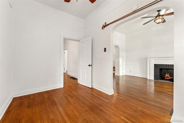 1748 S Logan St, Denver, CO 80210 - unfurnished living room with ceiling fan, arched walkways, wood finished floors, a brick fireplace, and baseboards