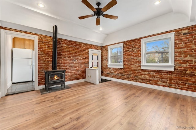 1748 S Logan St, Denver, CO 80210 - unfurnished living room with a wood stove, baseboards, light wood finished floors, ceiling fan, and brick wall