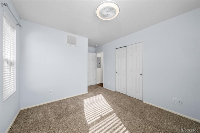 unfurnished bedroom featuring carpet flooring, electric panel, and a closet