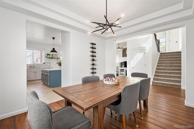 25362 E Indore Dr, Aurora, CO 80016 - dining space with a chandelier, stairs, a tray ceiling, and wood-type flooring