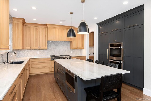 kitchen featuring sink, hanging light fixtures, stainless steel appliances, a center island, and light stone counters