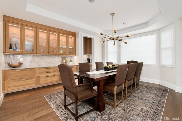 dining room with a raised ceiling, dark hardwood / wood-style floors, and a notable chandelier