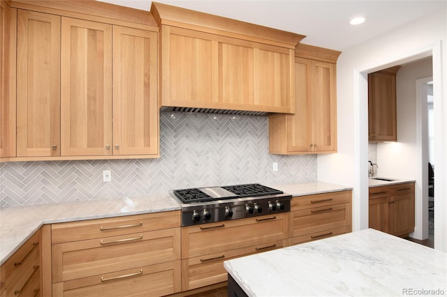 kitchen featuring sink, light stone counters, tasteful backsplash, stainless steel gas stovetop, and light brown cabinets