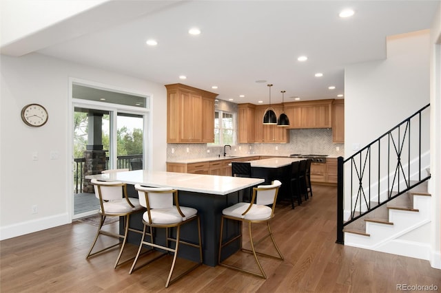 kitchen featuring pendant lighting, sink, dark wood-type flooring, tasteful backsplash, and a kitchen island