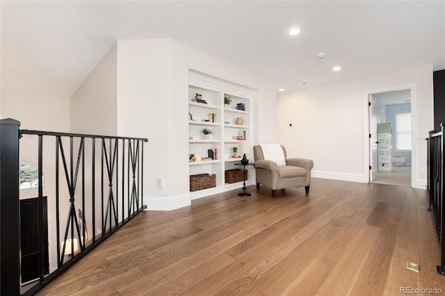 living area featuring built in shelves, plenty of natural light, and light hardwood / wood-style flooring