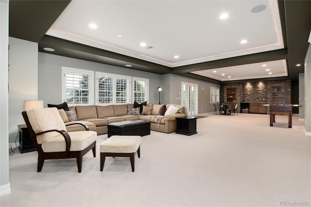 living room with light carpet, a tray ceiling, and ornamental molding