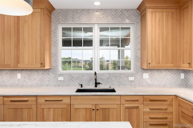 kitchen featuring light stone counters, sink, and backsplash