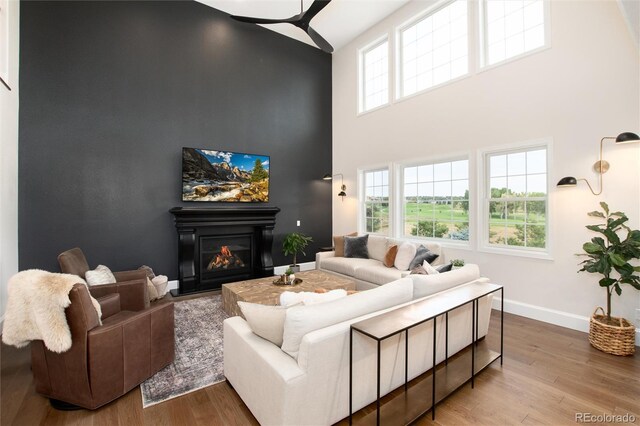 living room with a towering ceiling and wood-type flooring