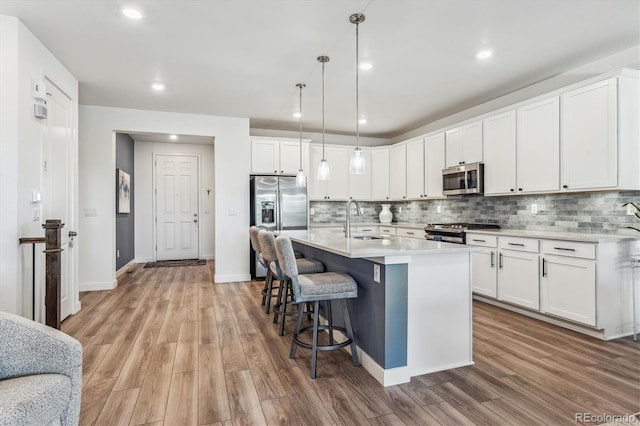 kitchen featuring sink, appliances with stainless steel finishes, wood-type flooring, and white cabinetry