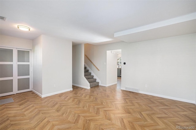 unfurnished room featuring stairway and baseboards