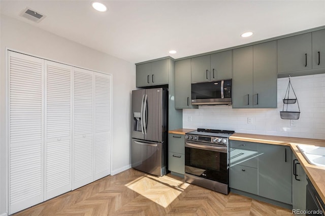 kitchen featuring stainless steel appliances, gray cabinets, butcher block countertops, tasteful backsplash, and recessed lighting