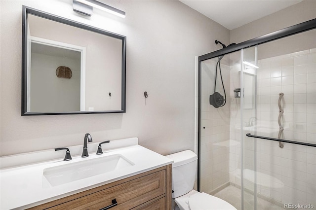 bathroom featuring a shower stall, toilet, and vanity