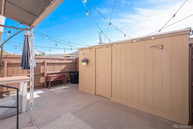 view of patio with a shed, fence, and an outbuilding