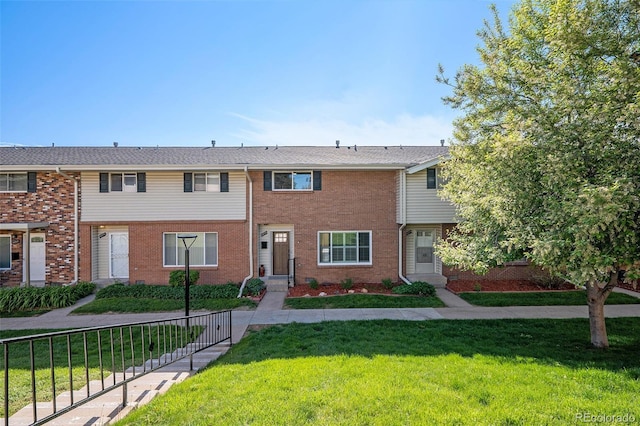 townhome / multi-family property with a front lawn and brick siding