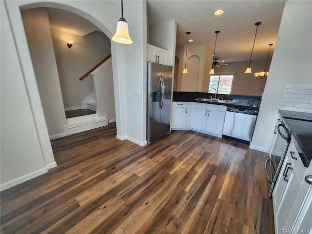 kitchen featuring pendant lighting, dark countertops, stainless steel appliances, and arched walkways