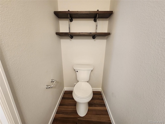 bathroom with baseboards, toilet, and wood finished floors
