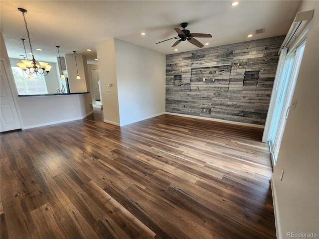 interior space with baseboards, recessed lighting, an accent wall, and ceiling fan with notable chandelier