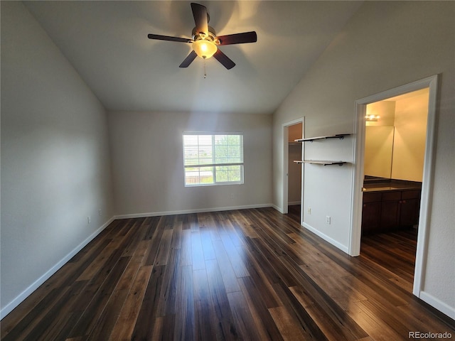 unfurnished bedroom with a closet, baseboards, vaulted ceiling, a spacious closet, and dark wood-style floors
