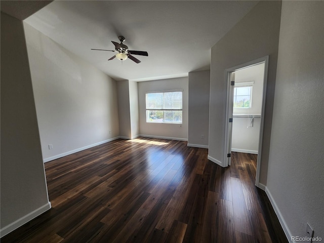 empty room with ceiling fan, baseboards, and dark wood finished floors