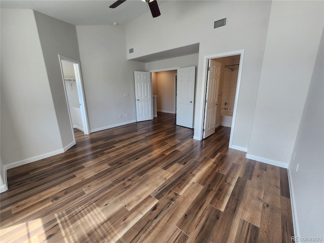 unfurnished bedroom featuring dark wood-style flooring, baseboards, high vaulted ceiling, and visible vents