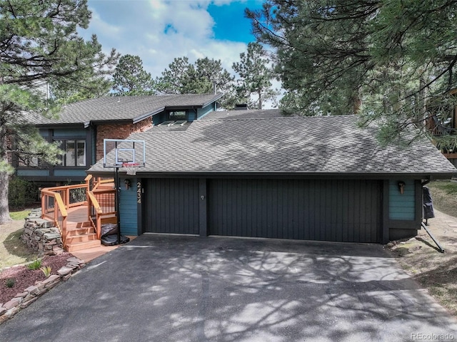 view of front of house featuring an attached garage, a shingled roof, aphalt driveway, and stairway