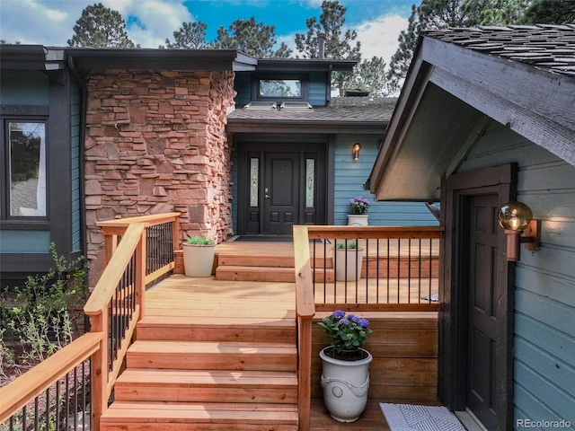 view of exterior entry with a wooden deck and stone siding