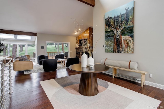 interior space featuring wood finished floors, a fireplace, beamed ceiling, baseboards, and high vaulted ceiling