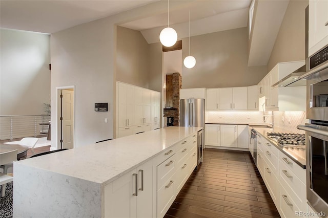 kitchen featuring backsplash, high vaulted ceiling, appliances with stainless steel finishes, and light stone countertops