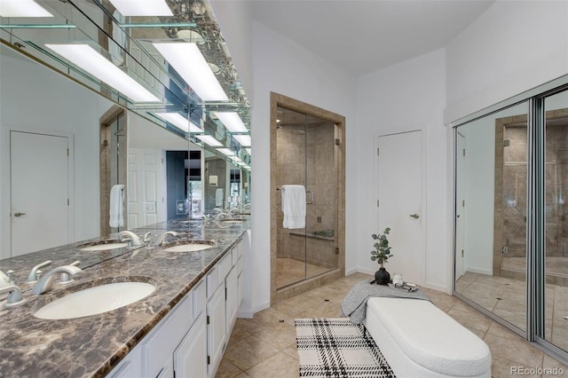 bathroom featuring tile patterned flooring, a sink, a freestanding bath, and a shower stall
