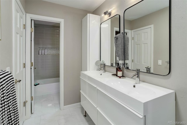 bathroom featuring double vanity, baseboards, a sink, and marble finish floor