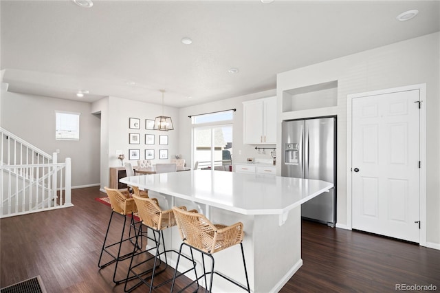 21925 E 44th Pl, Aurora, CO 80019 - kitchen with stainless steel fridge, light countertops, dark wood-style flooring, a kitchen breakfast bar, and recessed lighting