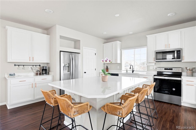 21925 E 44th Pl, Aurora, CO 80019 - kitchen featuring appliances with stainless steel finishes, a kitchen bar, a center island, dark wood-style flooring, and recessed lighting