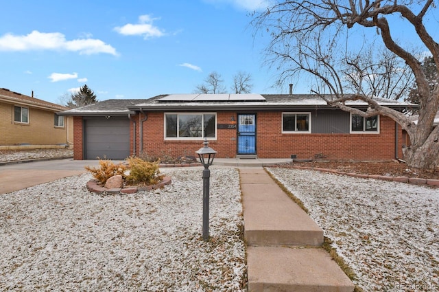 ranch-style home featuring a garage and solar panels