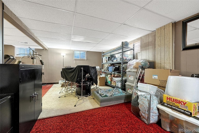 interior space with wooden walls, carpet flooring, and a drop ceiling