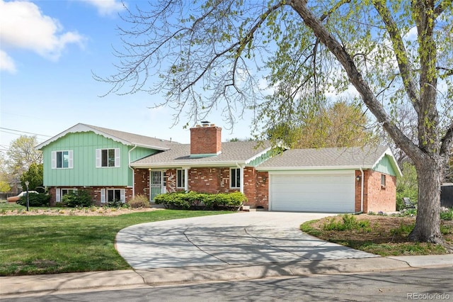 tri-level home with driveway, a chimney, brick siding, an attached garage, and a front yard