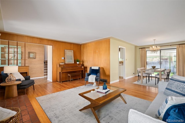 living room with an inviting chandelier, wood walls, wood finished floors, and baseboards