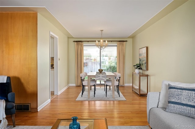 dining room featuring baseboards, an inviting chandelier, visible vents, and light wood-style flooring