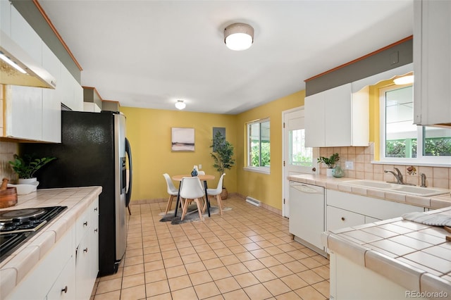 kitchen featuring white dishwasher, backsplash, tile countertops, and a sink