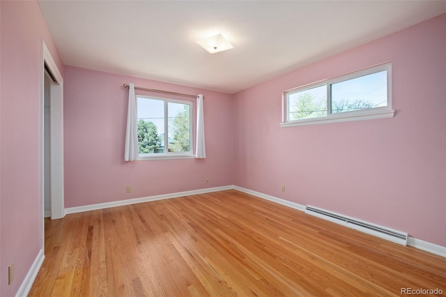 unfurnished bedroom featuring baseboards, light wood-style floors, a baseboard radiator, and multiple windows