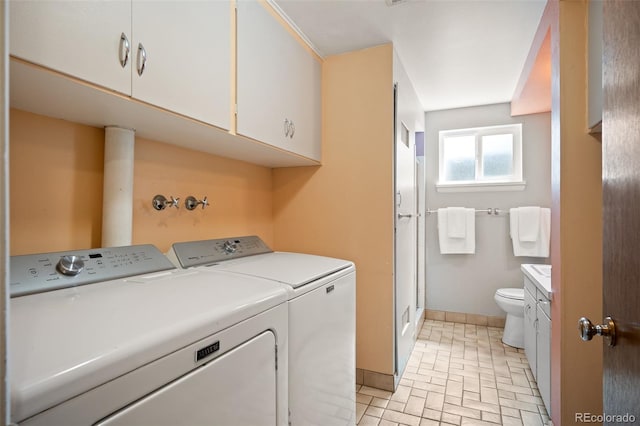 laundry room with washing machine and dryer, brick floor, baseboards, and laundry area