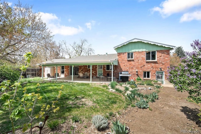 back of property with board and batten siding, a patio area, a lawn, and brick siding