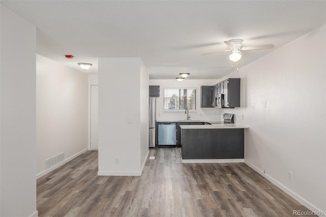 kitchen featuring ceiling fan, dark hardwood / wood-style floors, a textured ceiling, and appliances with stainless steel finishes